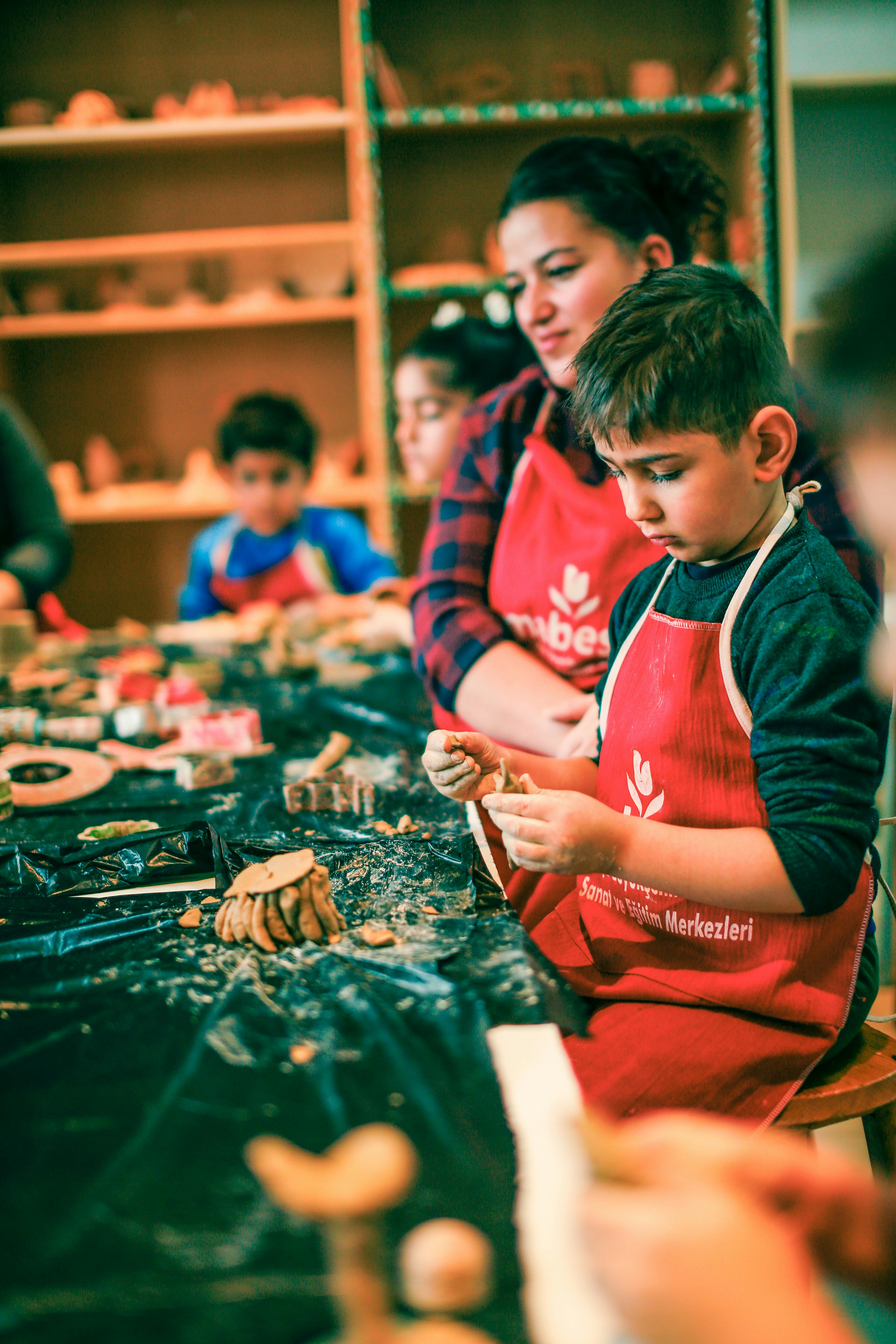 Children creating pottery under the guidance of an instructor in a fun and educational ceramics workshop.