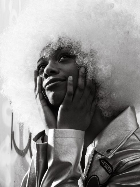 Dramatic black and white portrait of a fashion model with white afro hairstyle, exuding elegance and style.