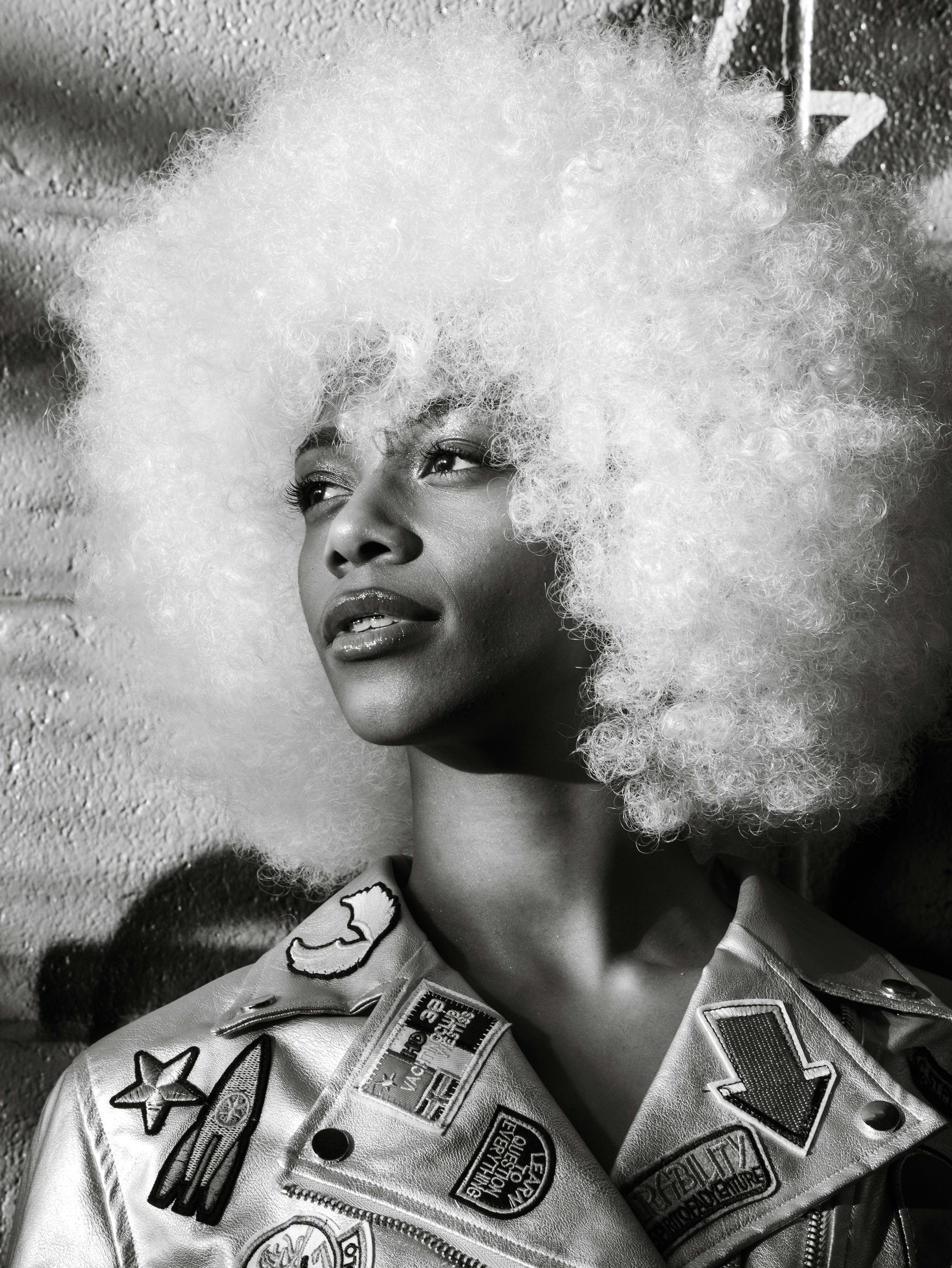 a woman with an afro wearing a leather jacket