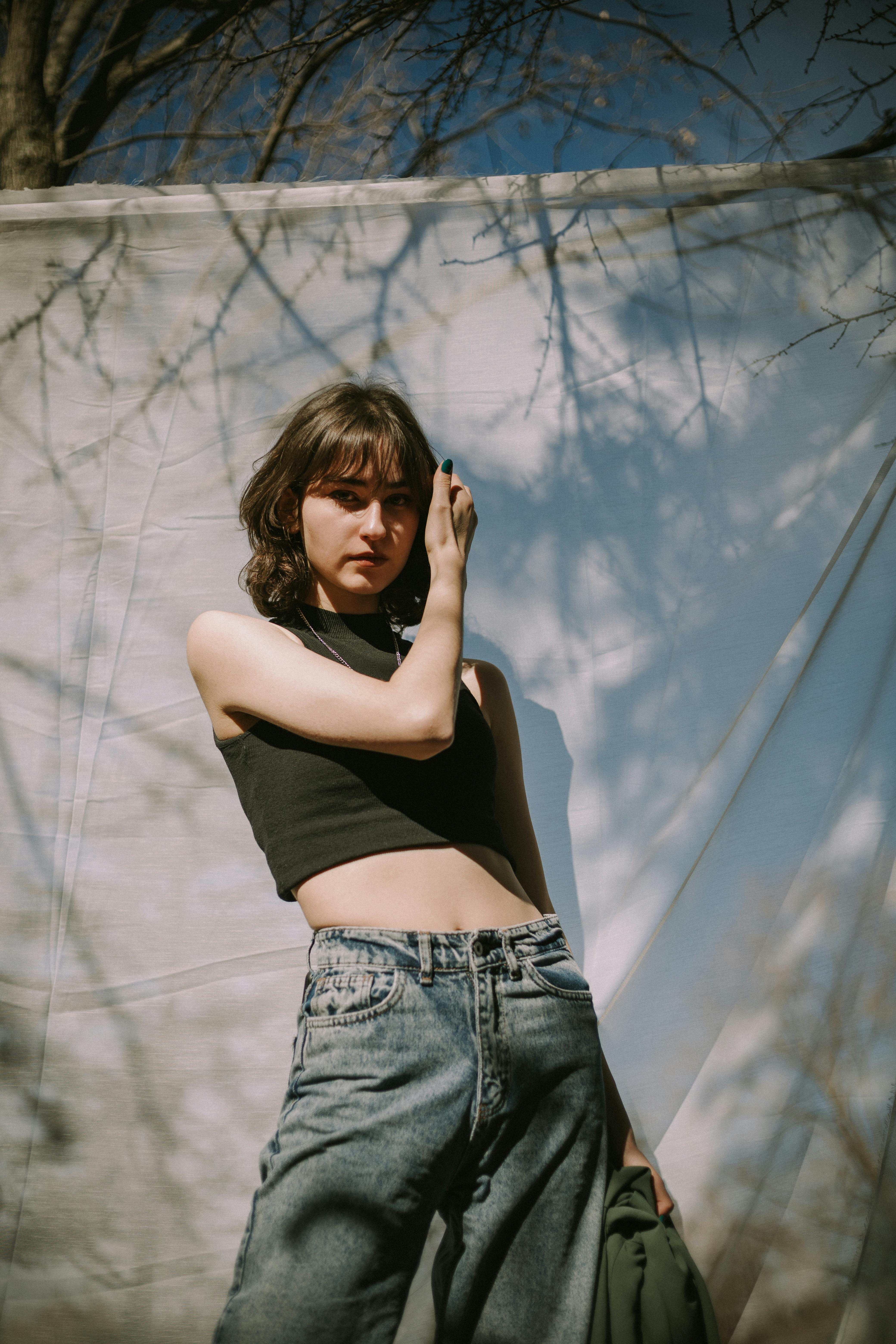 Fashionable woman posing in natural light wearing jeans and a black top.