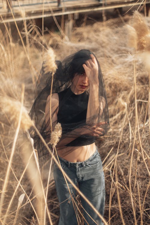 A woman in a black top and jeans standing in tall grass