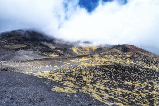 A stunning landscape view of Mount Etna's rocky terrain and cloud-covered summit.