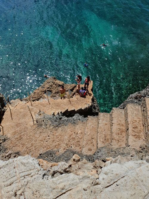 Free Visitors exploring and enjoying the scenic cliffside steps by the ocean in Siquijor, Philippines. Stock Photo