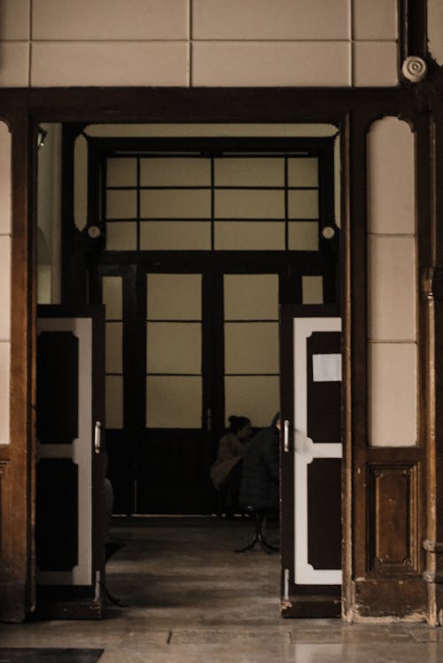 People Sitting Inside an Old Building Photographed through Open Door 