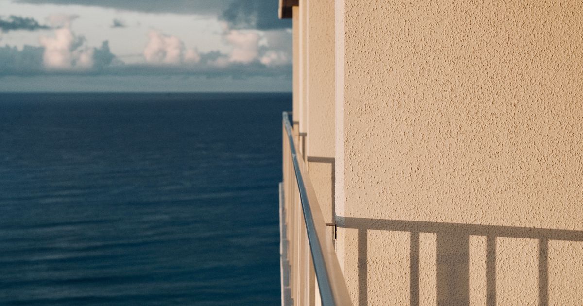 Vista calma do oceano de um balcão em Honolulu, Havai, mostrando um céu claro e a fachada de um prédio.