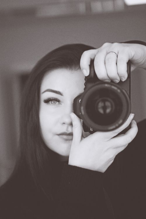 Free Monochrome portrait of a woman holding a camera, capturing a self-portrait. Stock Photo