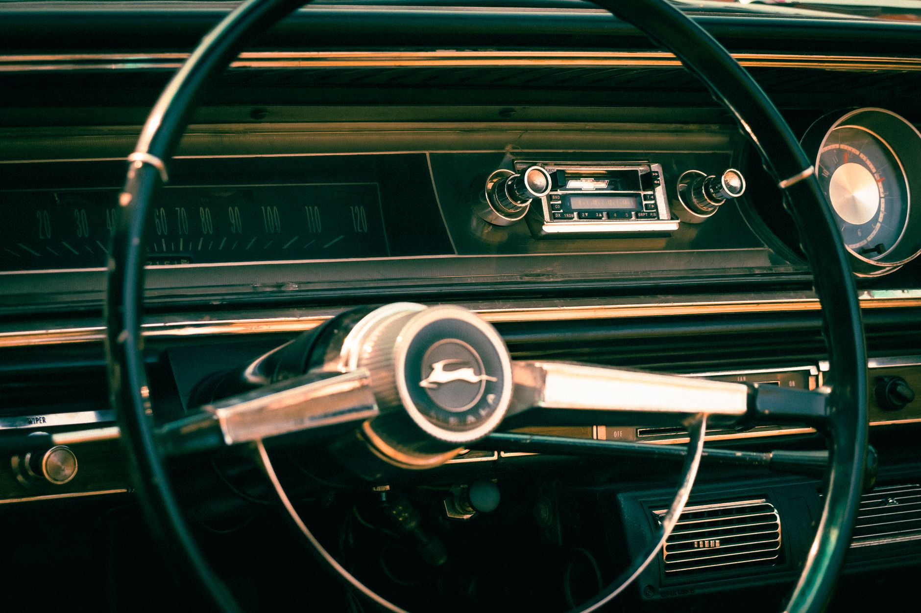 Close-up of a vintage Chevrolet Impala steering wheel, highlighting retro design and classic details.