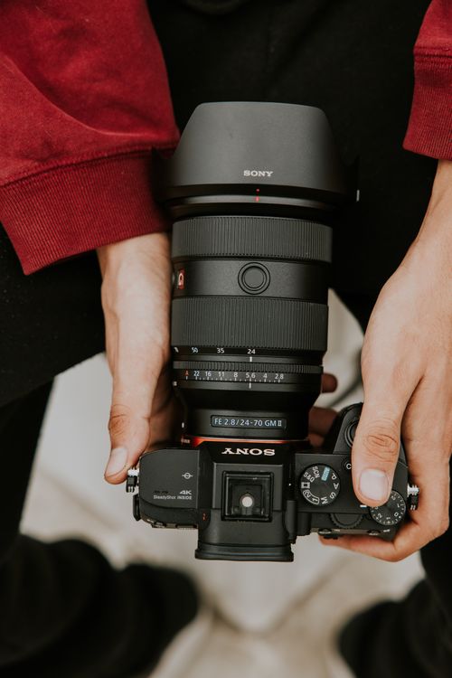 Free A close-up image showcasing a DSLR camera held by a photographer, emphasizing focus and equipment. Stock Photo