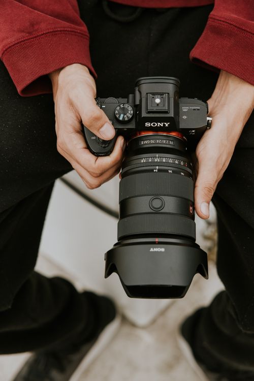 Free Close-up of a photographer's hands holding a professional camera, showcasing photography equipment. Stock Photo
