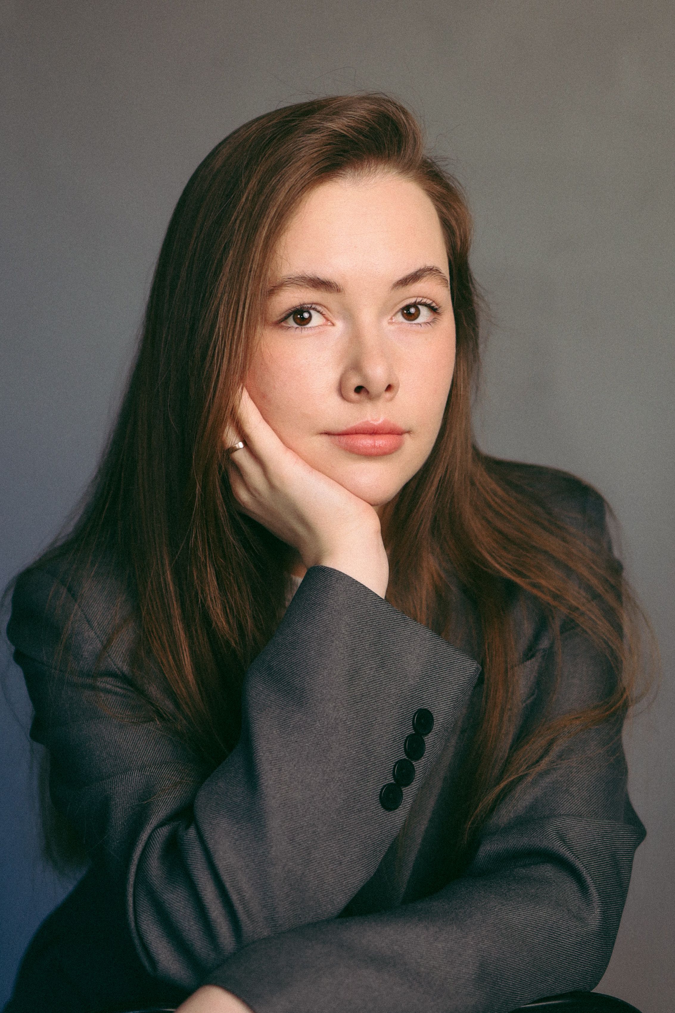 Studio portrait of a young woman with long hair in a sophisticated jacket, conveying elegance and calmness.