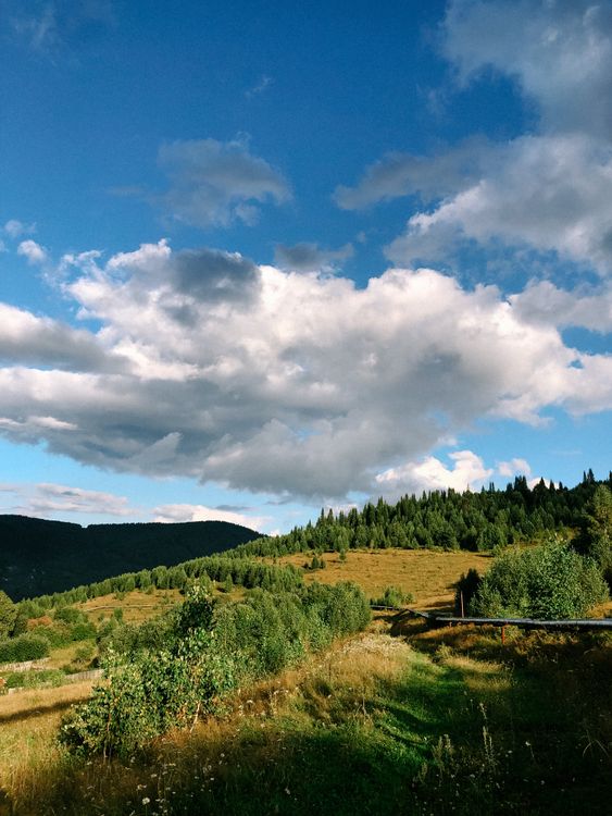 Free Idyllic summer view of lush green countryside and mountains under a blue sky. Stock Photo