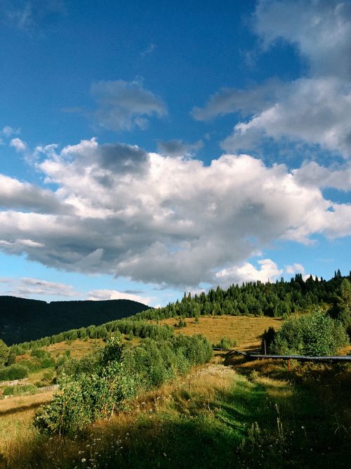Free Idyllic summer view of lush green countryside and mountains under a blue sky. Stock Photo