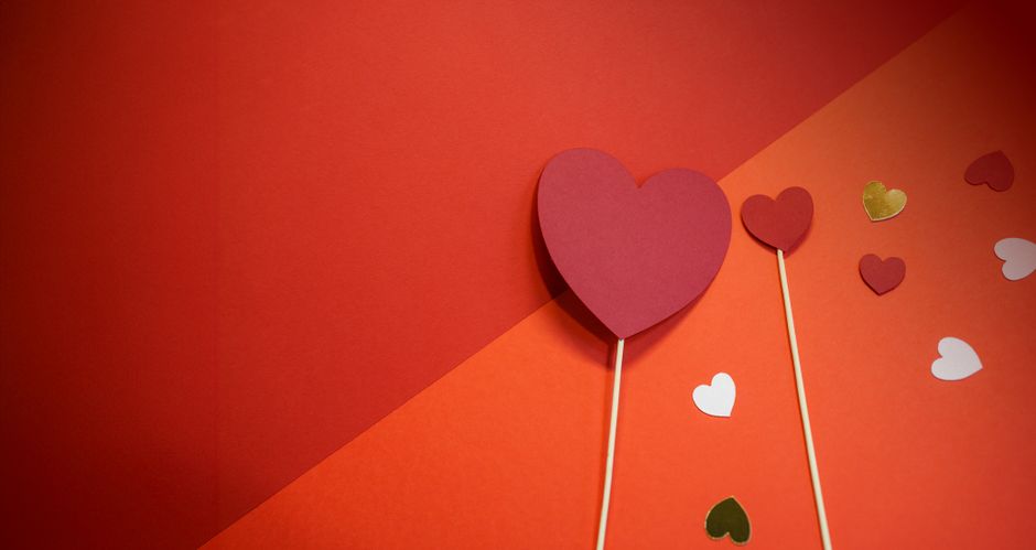 Flat lay of red paper hearts on a red background, perfect for Valentine's decor.