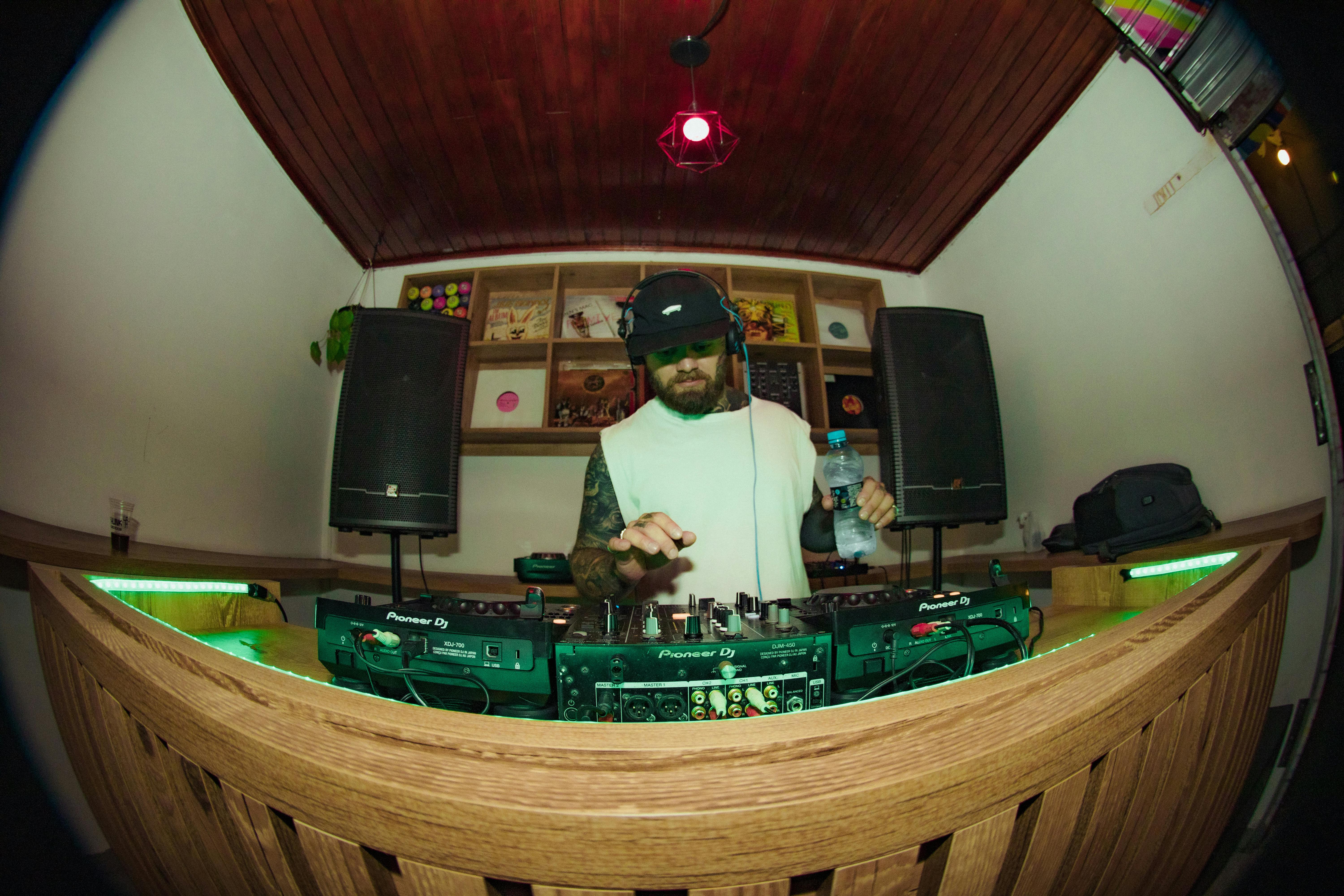 A DJ playing music with professional equipment in a vibrant nightclub setting.