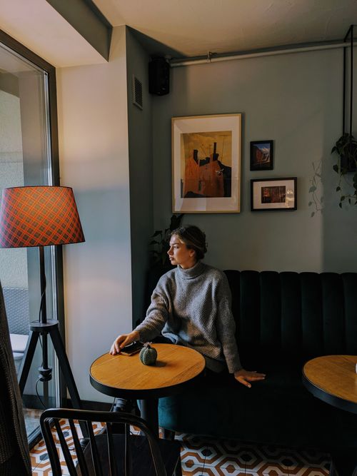 Free A woman sits in a cozy café by the window, enjoying the warm ambiance. Stock Photo