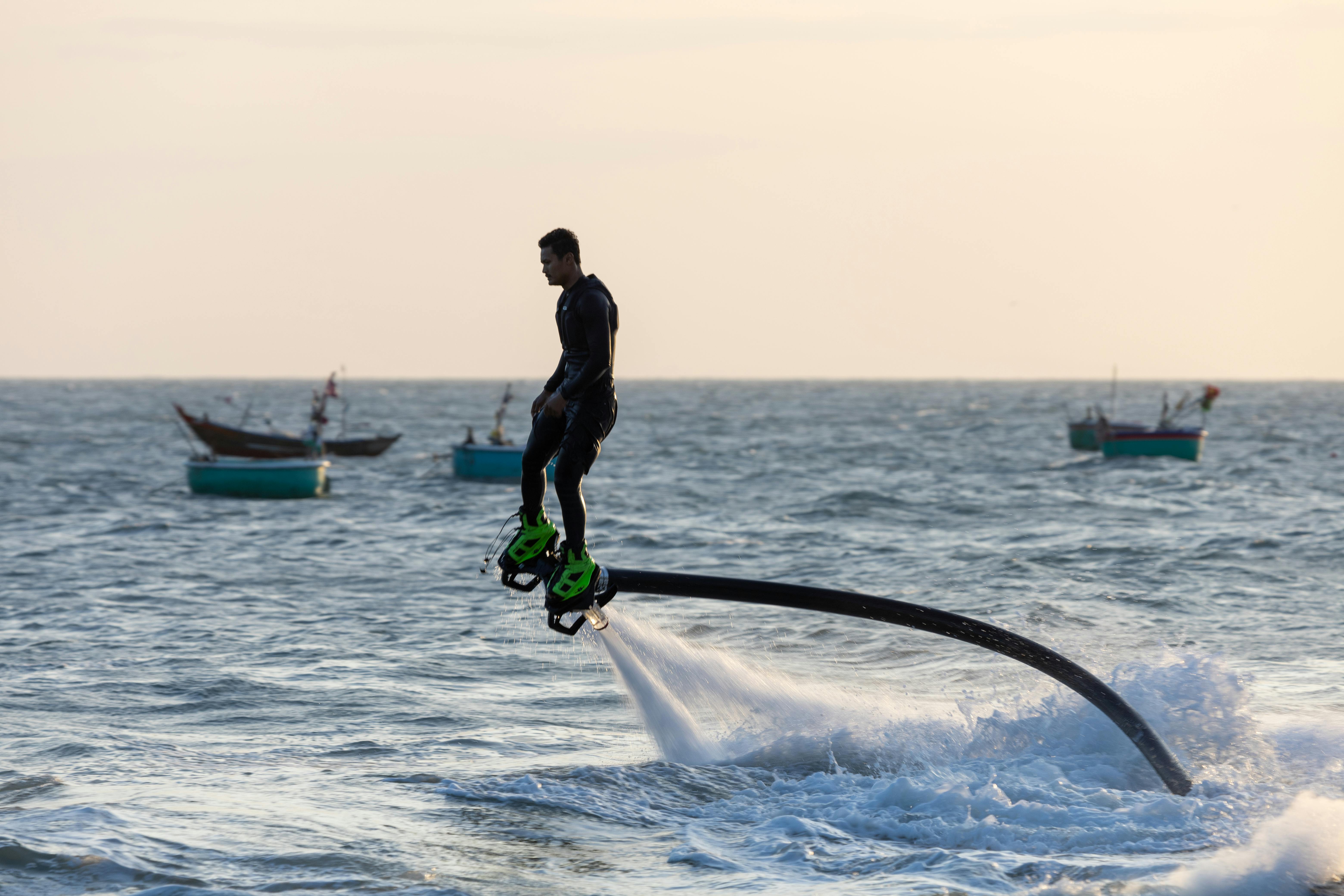 A man flyboards above the ocean, showcasing dynamic watersport adventure at sunset.