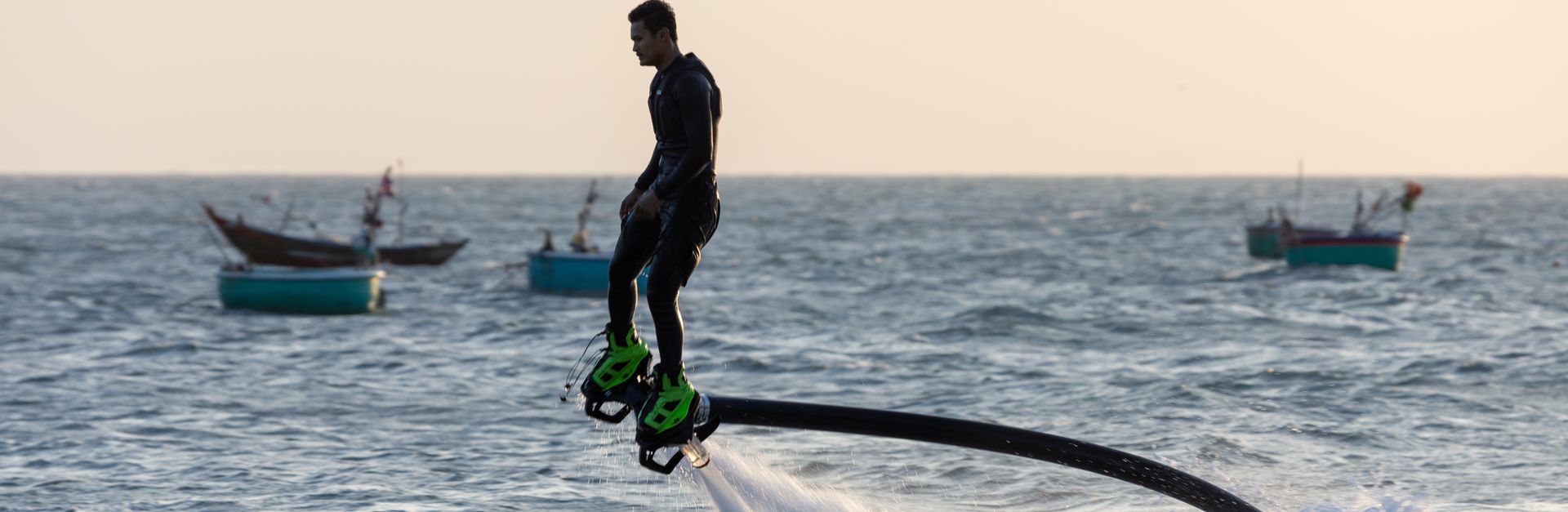 A man flyboards above the ocean, showcasing dynamic watersport adventure at sunset.