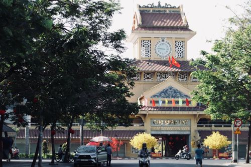 Free Scenic view of the iconic Binh Tay Market entrance with surrounding trees and vibrant flags in Ho Chi Minh City, Vietnam. Stock Photo