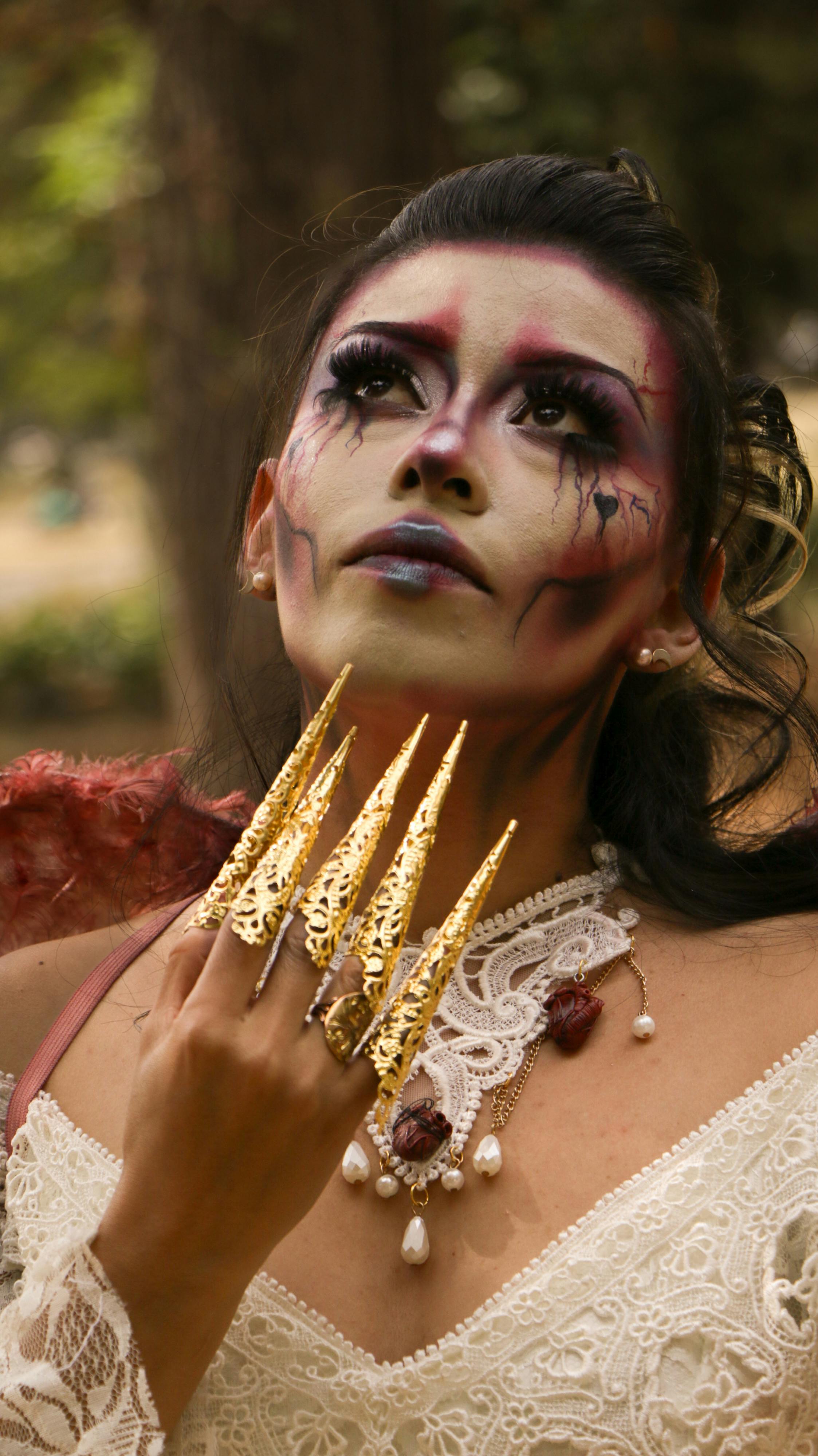 Free Mysterious woman in gothic cosplay with dramatic makeup and gold claw-like accessories outdoors. Stock Photo