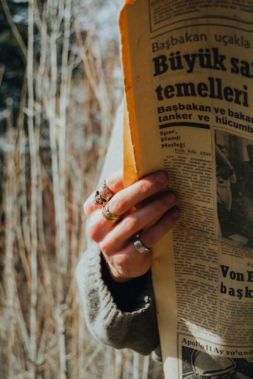 A person holding a newspaper with the words, buy and sell