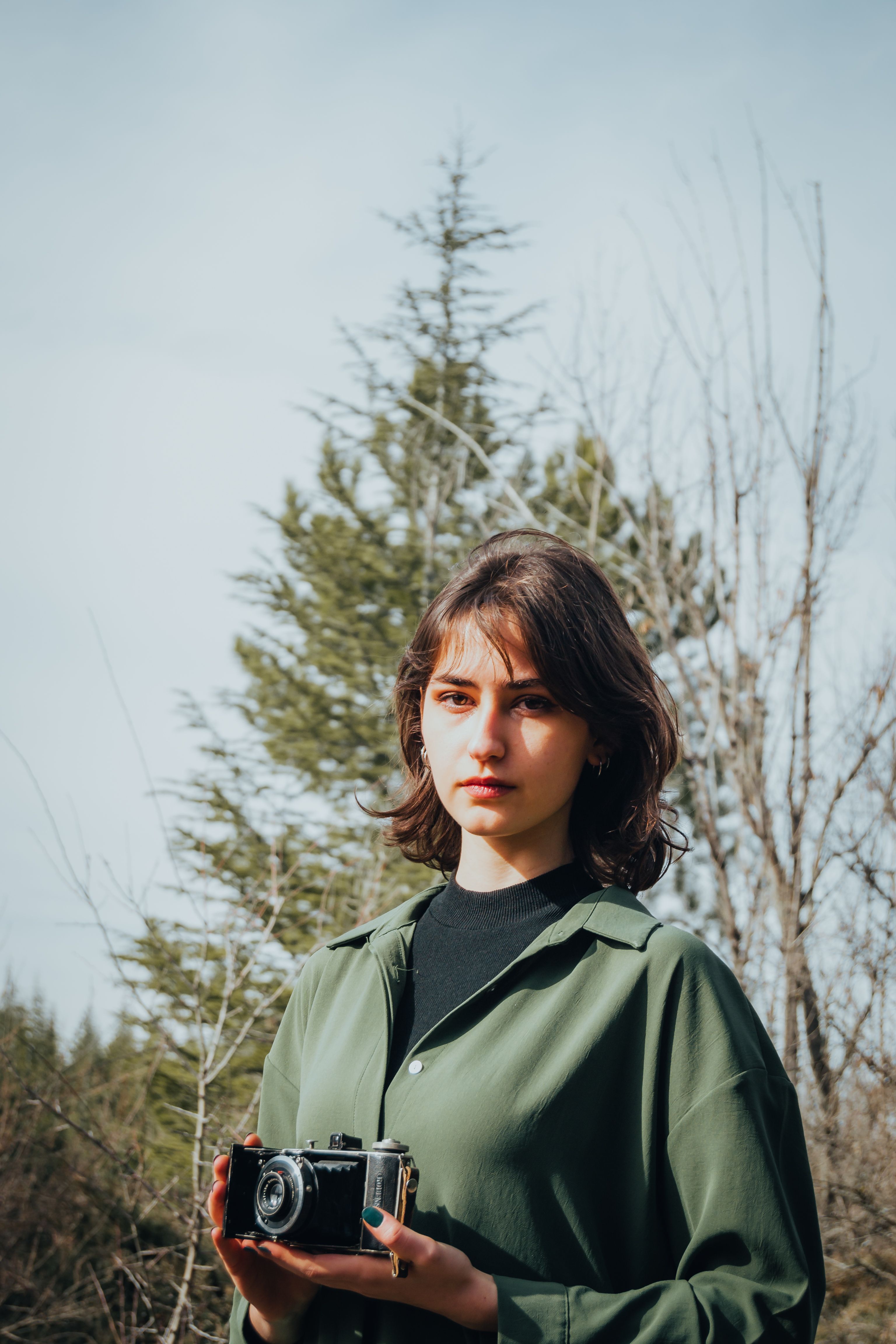 A woman holding an old camera in the woods · Free Stock Photo