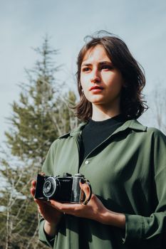 Portrait of a young woman with a vintage camera in a natural setting