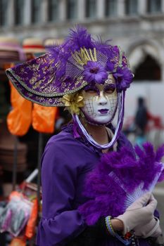 A captivating portrait of a woman in purple attire at the Venetian carnival, showcasing intricate mask and hat.