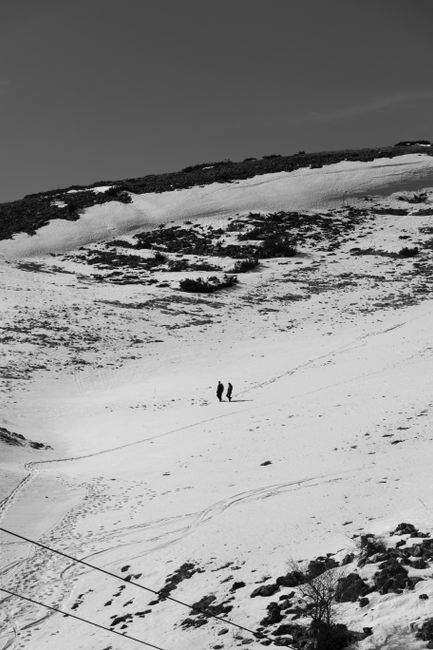 Two people hiking on a snowy hill in Mavrovo, North Macedonia.