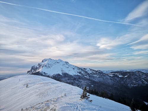 A snowy mountain with a plane flying over it