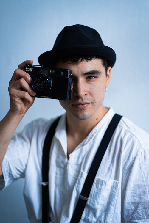 Model in White Shirt Suspenders and Fedora Holding a Camera