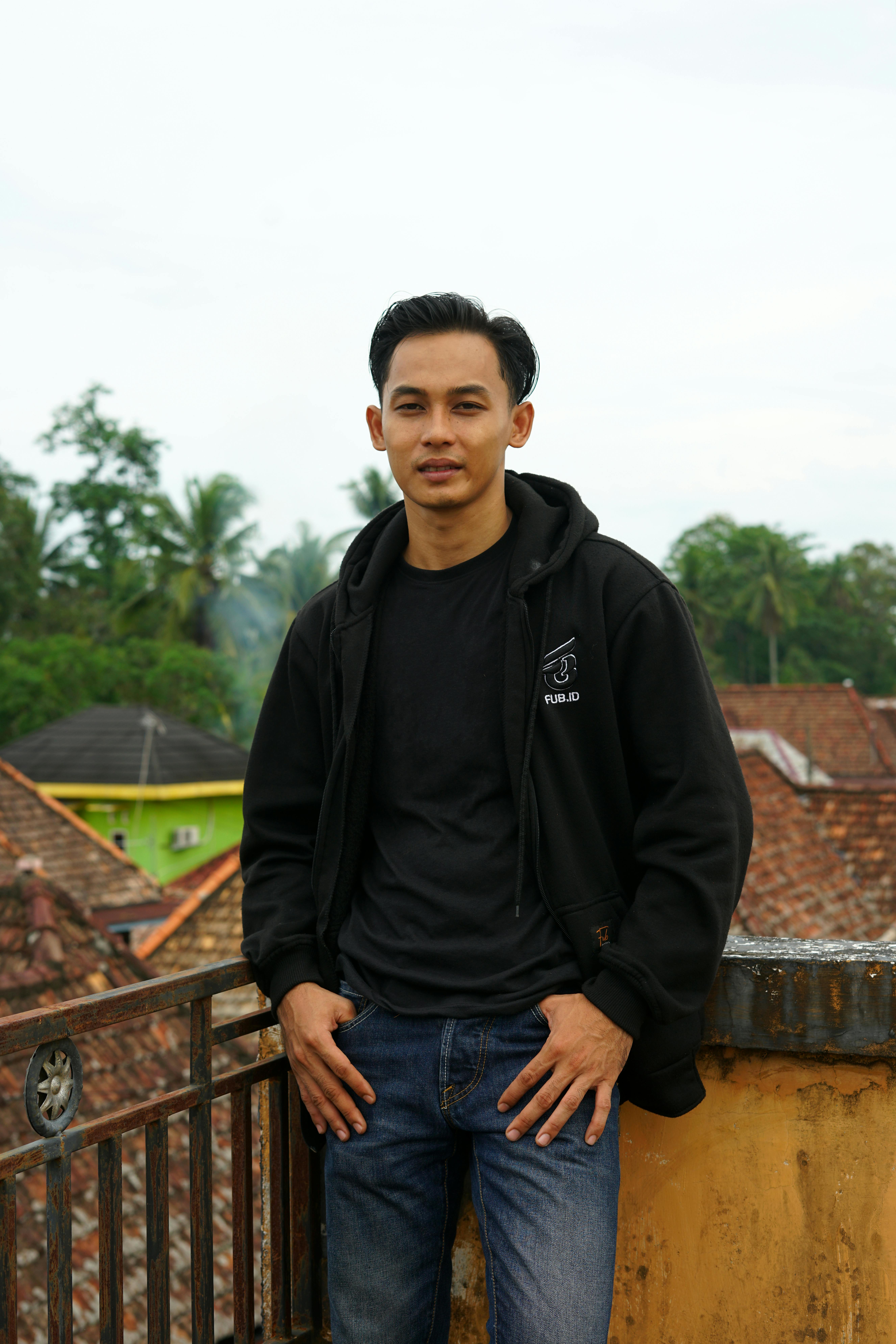Relaxed portrait of a young man in casual attire on a rooftop.