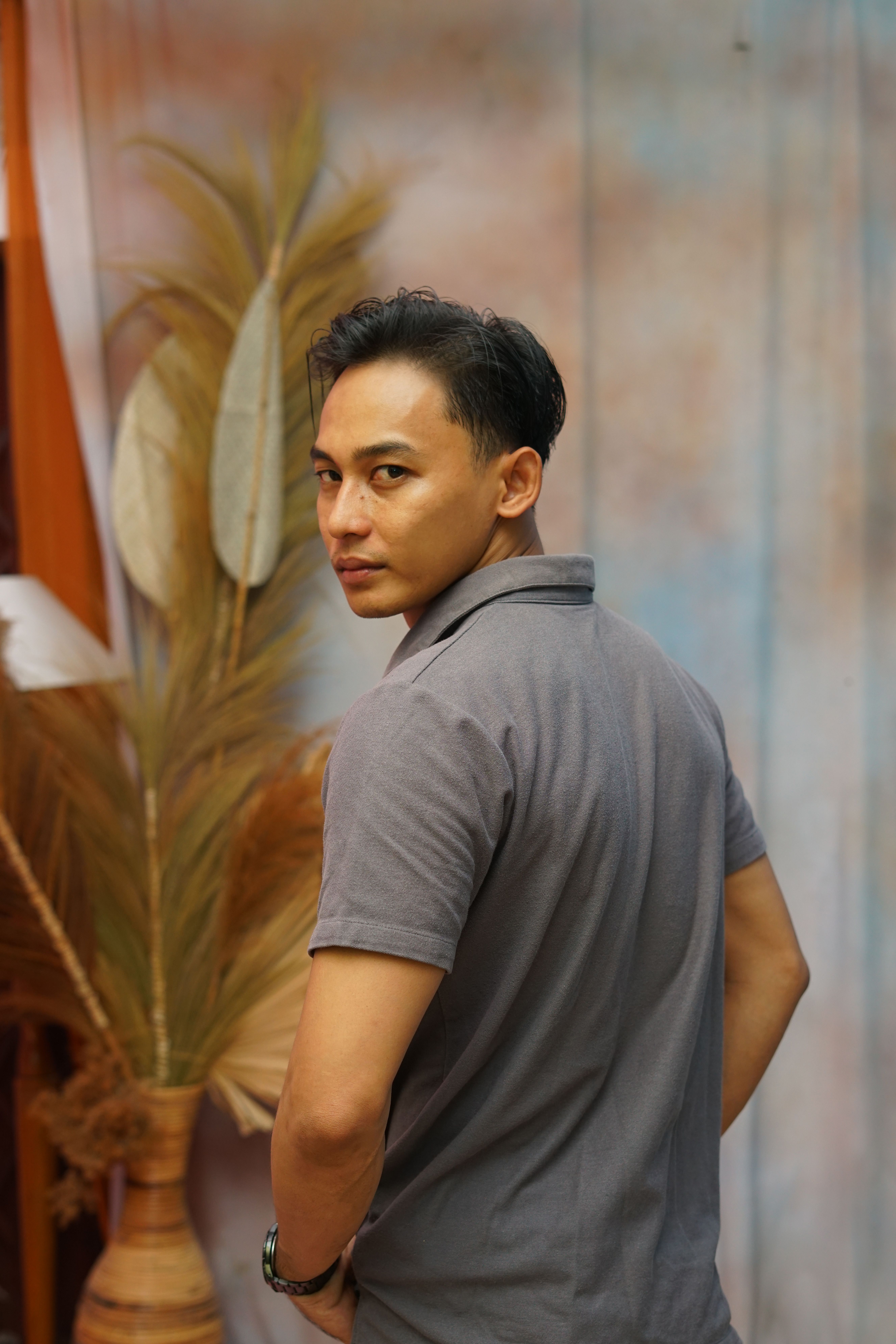 Stylish young adult posing in a creative indoor setting with rustic decor.