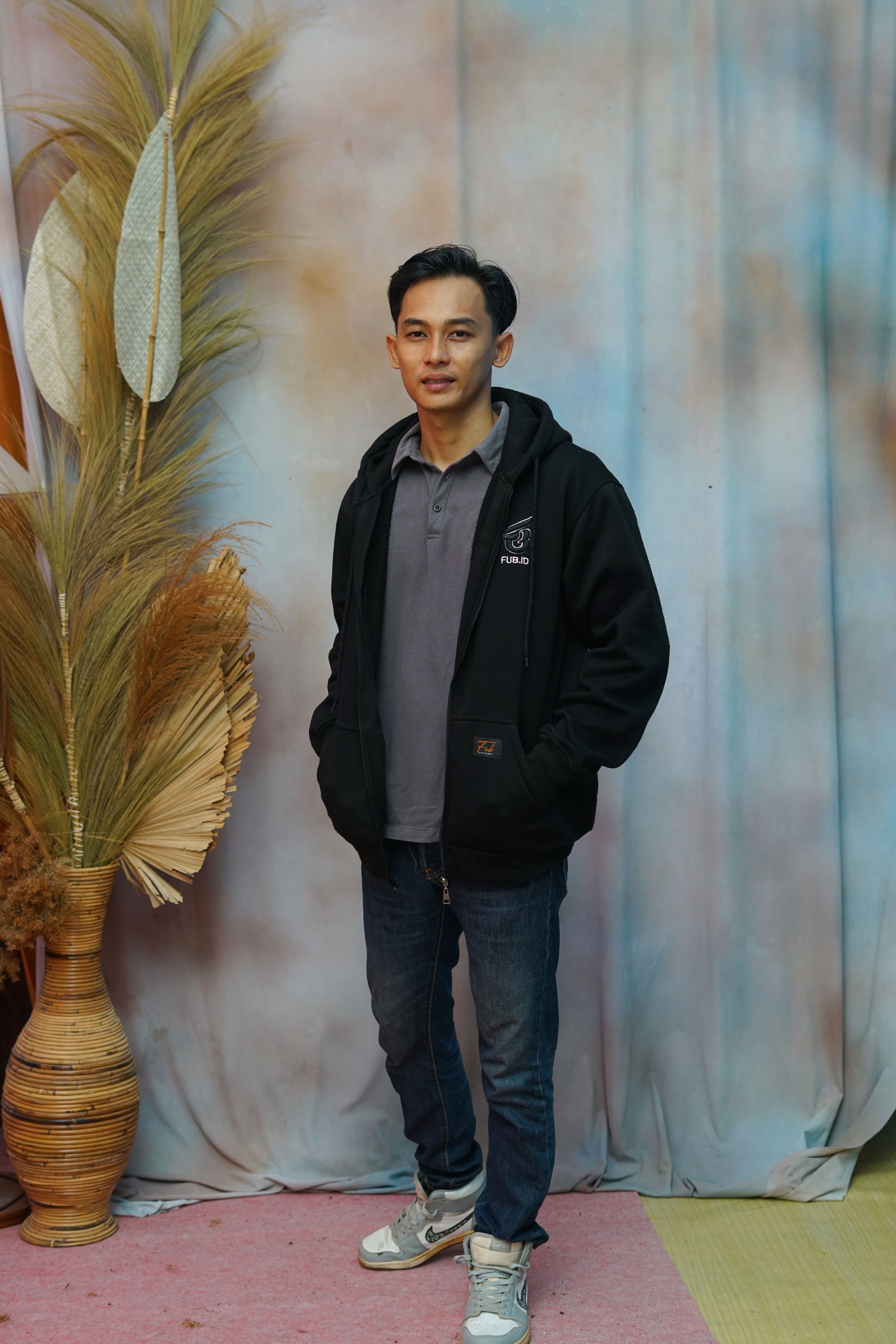 A relaxed portrait of a man dressed casually with a natural backdrop.