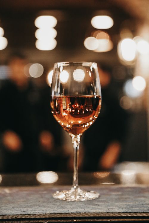 Free A glass of red wine elegantly placed with a warm bokeh background. Stock Photo