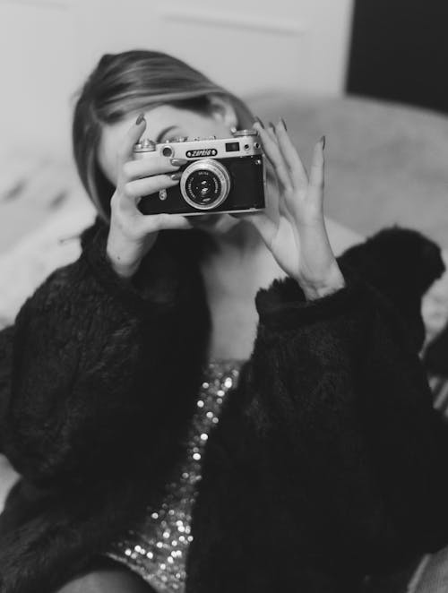 Black and White Photo of a Woman Taking a Picture with a Film Camera 