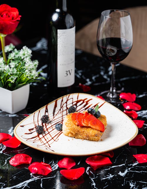 Fruit Cake and Wine on Table with Flowers Petals