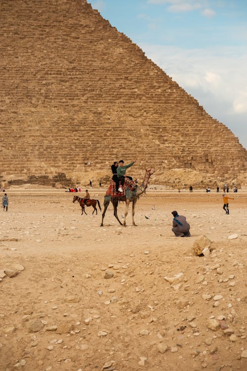 A man riding a camel in front of the great pyramid