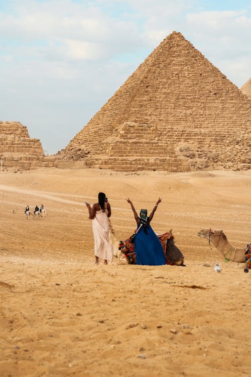 Two people are standing in front of the pyramids
