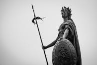 一张单色照片中，一尊手持长矛和盾牌的经典雕像散发着永恒的力量