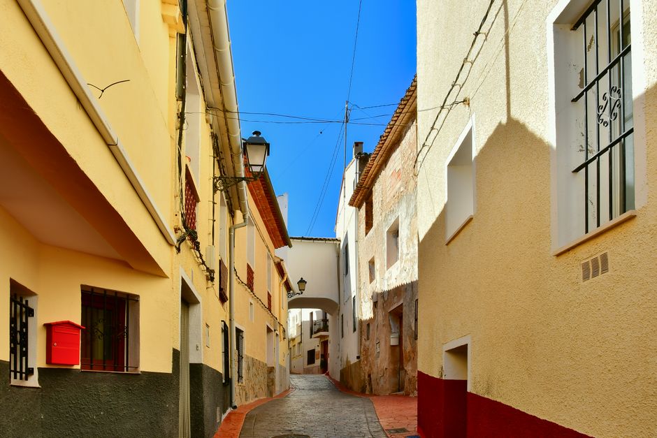 Callejón pintoresco en Beniardá, España, que muestra arquitectura tradicional bajo cielos azules claros.