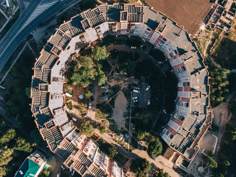 Top-view drone shot of a circular residential district surrounded by greenery.