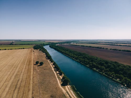 River and Fields under Clear Sky on Plains