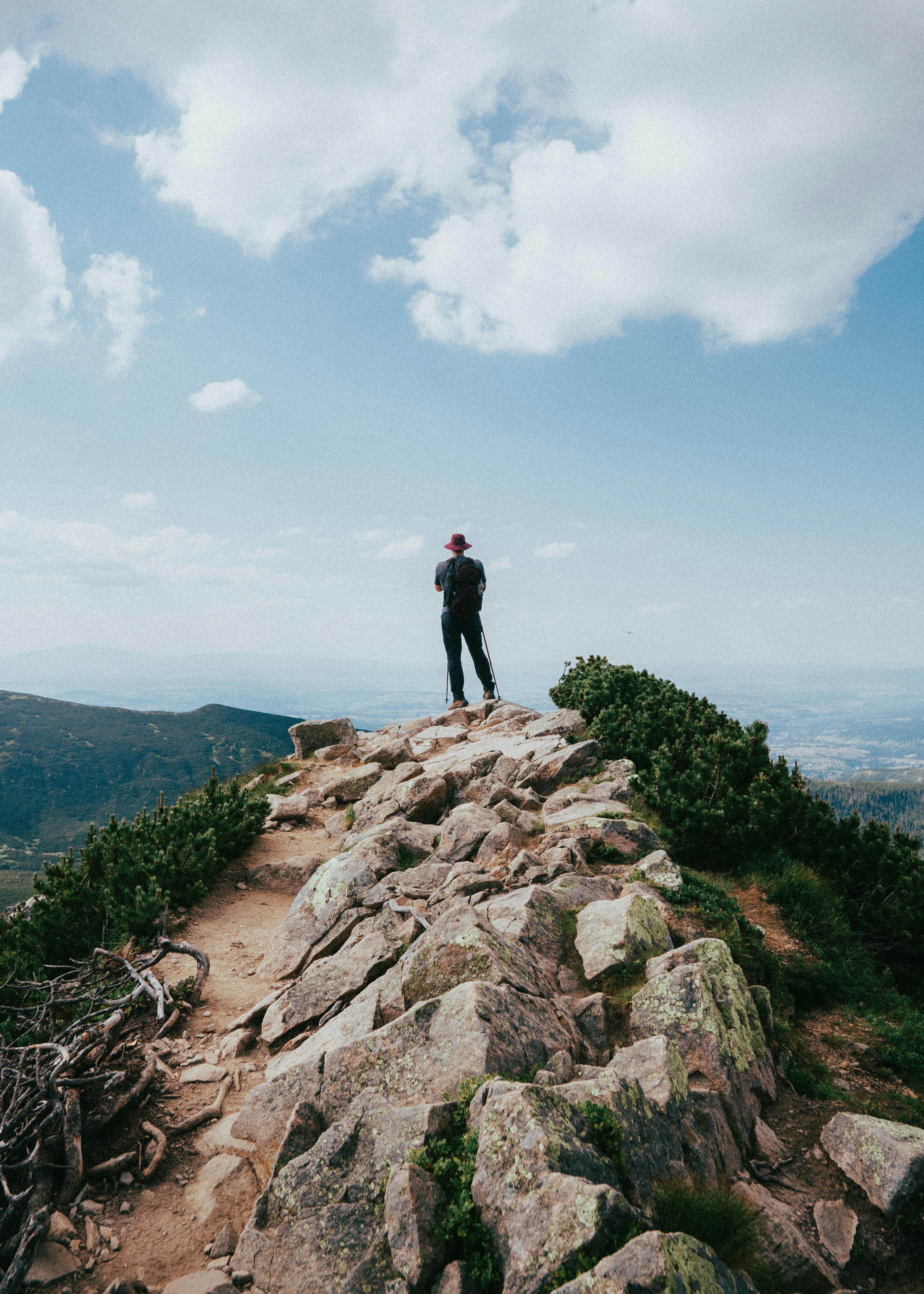 Man enjoying mountain view in Zakopane, Poland, standing on a rocky summit with a backpack.