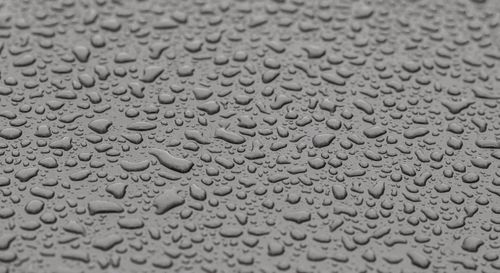 Free A detailed still-life image of water droplets on a textured gray surface, showcasing texture and contrast. Stock Photo