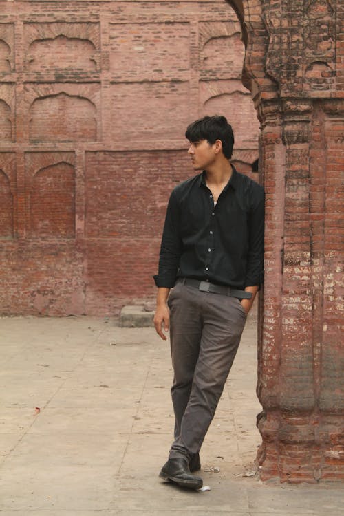 Young Man in a Black Shirt and Gray Pants Posing in the Ruins