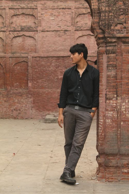 Free Man poses thoughtfully against a historic brick wall, exuding style and confidence. Stock Photo