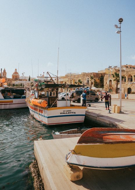 Vibrant boats docked in picturesque Marsašlokas harbor, showcasing traditional Maltese culture.