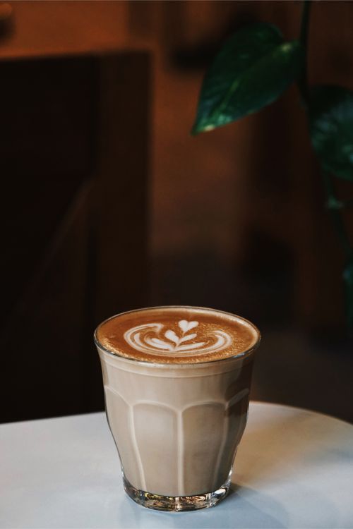 Free A beautifully crafted cappuccino with latte art in a cozy cafe setting. Stock Photo