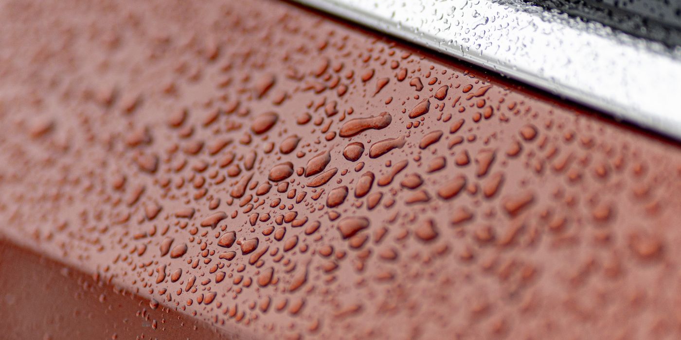 Water beading in tight droplets on red car paint