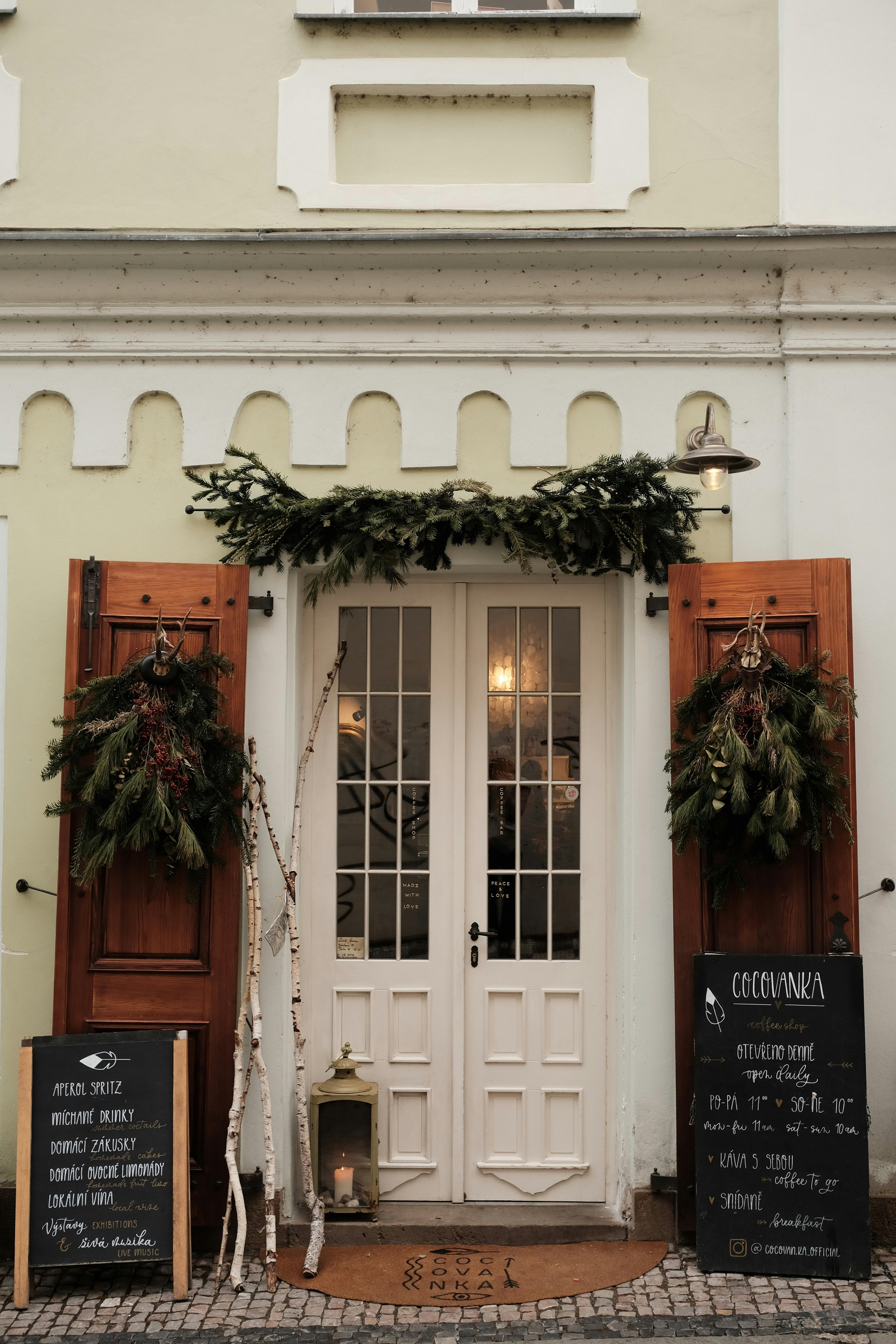Elegant café entrance in Prague with festive winter decorations and rustic charm.